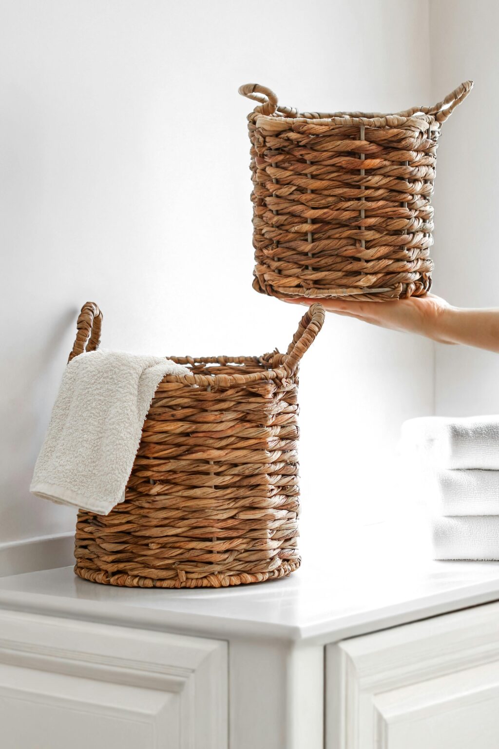 Stylish wicker baskets with towels in a bright, modern bathroom setting, showcasing minimalistic interior design.